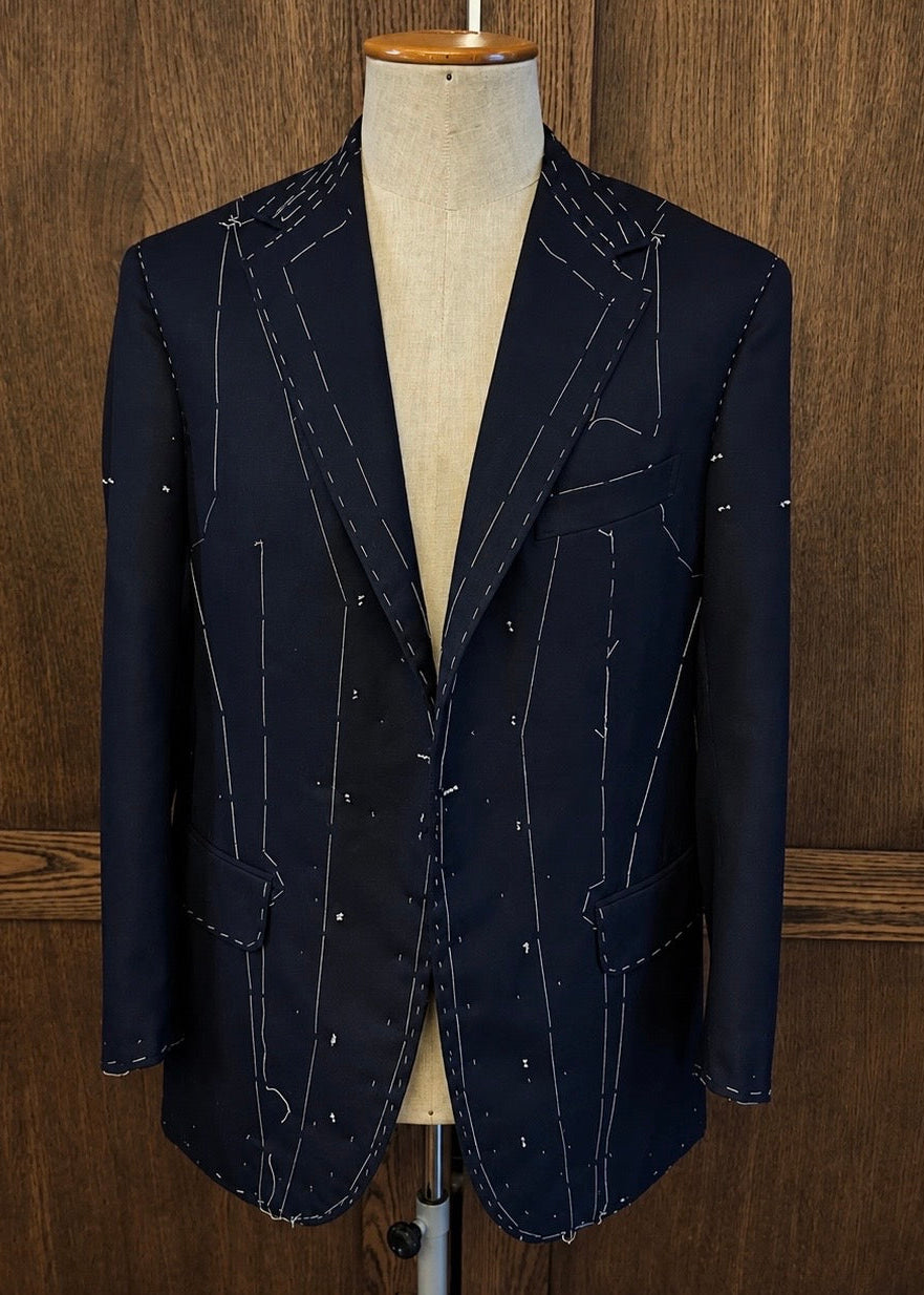 Bespoke suit jacket with basting stitches on mannequin at Isalium London
